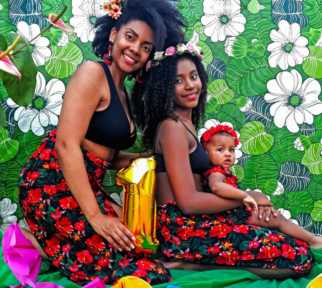 Monique Isis e suas filhas. Como mãe, ela conta como cria duas meninas negras, pensando em proteger a infância e juventude da população negra. 